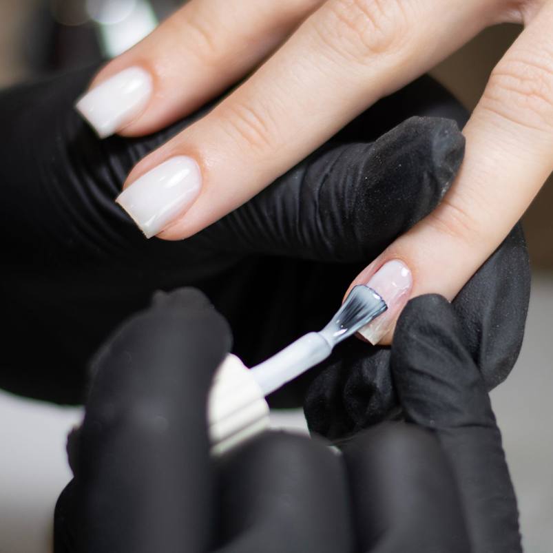 Nail technician applying nailpolish to client's fingernails 