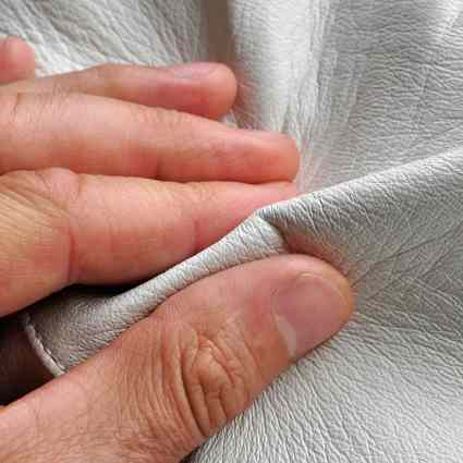 Person using hands to assess the texture of leather