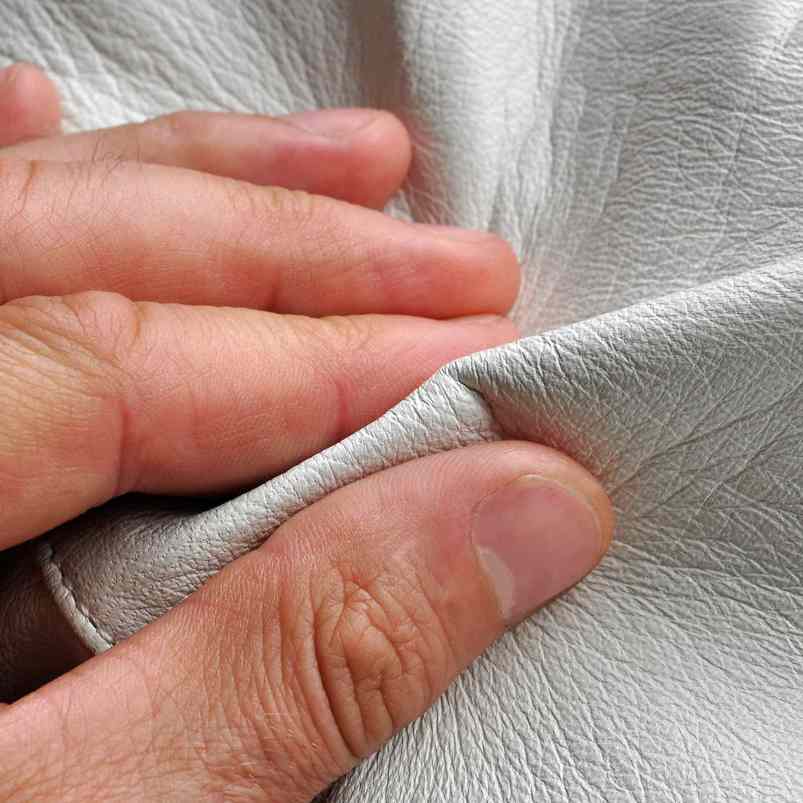 Person using hands to assess the texture of leather