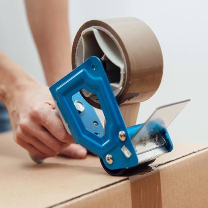 Person taping a cardboard box closed with brown tape