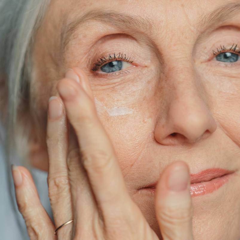 Senior person applying cream to face